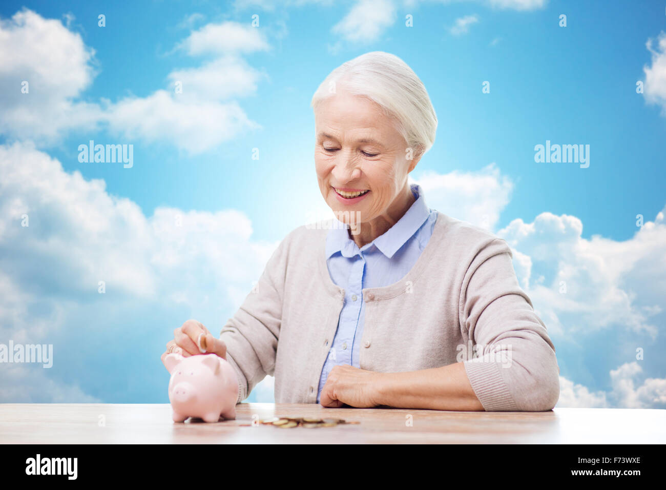 senior woman putting money to piggy bank Stock Photo - Alamy