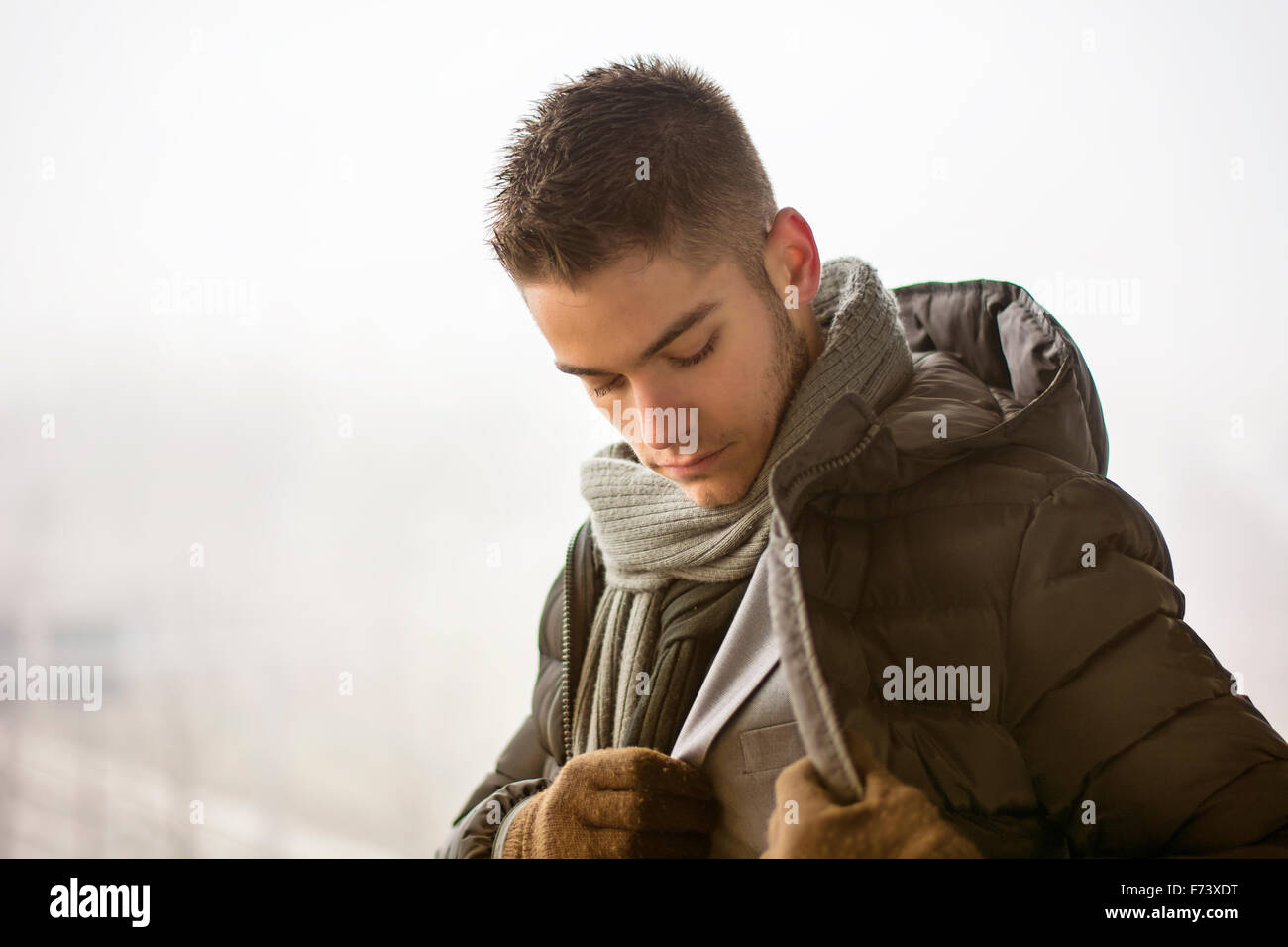 Profile view of handsome young man outdoor in winter wearing scarf, looking away thinking Stock Photo
