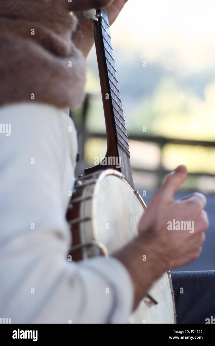 Hipster playing banjo in a country setting Stock Photo