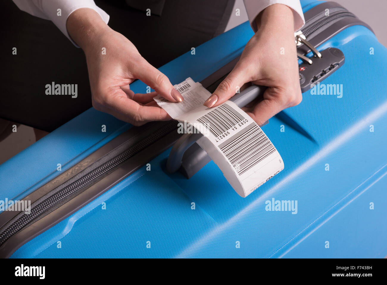 Airline check in luggage tag being attached to a suitcase Stock Photo