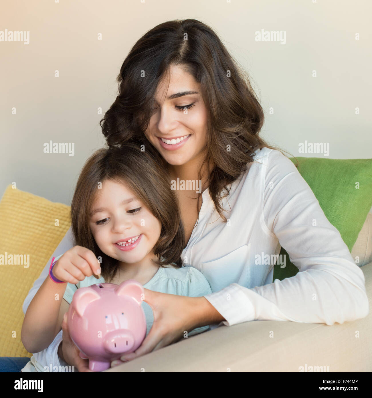 Mother and daughter putting coins into piggy bank Stock Photo - Alamy