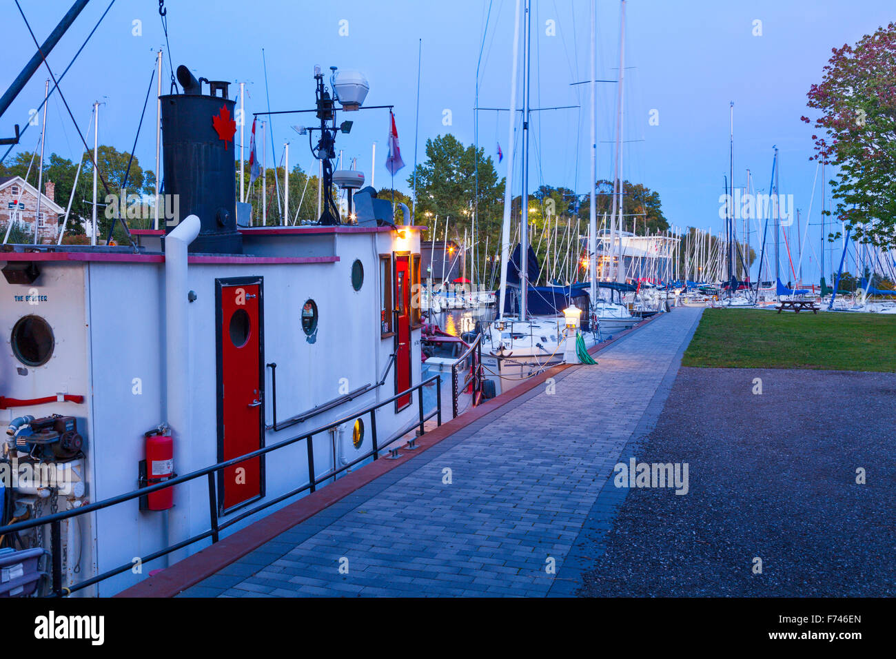 A tugboat with sailboats at the Oakville Harbour at sunset. Shipyard Park, Oakville, Ontario, Canada. Stock Photo