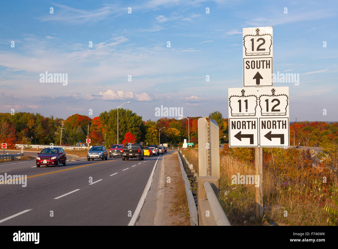 Road signs pointing to Highway 12 and Highway 11 on the side of a busy highway. Orillia, Ontario, Canada. Stock Photo