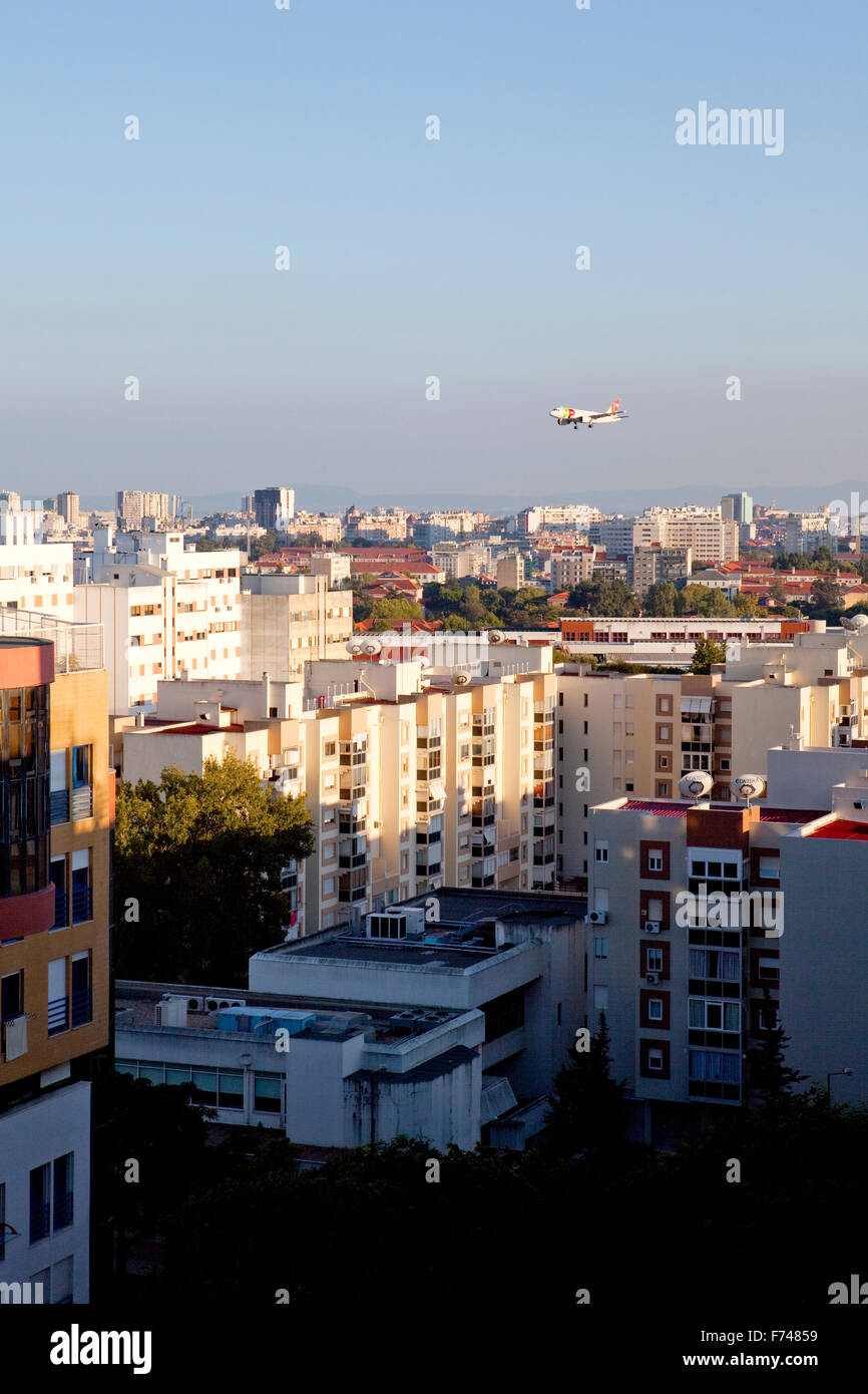 A plane flying over the buildings of Lisbon, before landing at the Lisbon Portela Airport, Portugal. Stock Photo