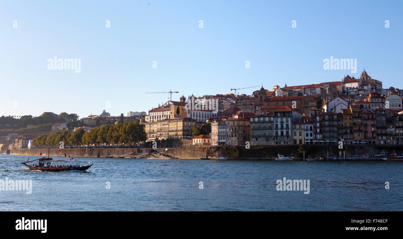 A panoramic view of a barge sailing in the summery evening on the Douro River in Porto, Portugal. Stock Photo