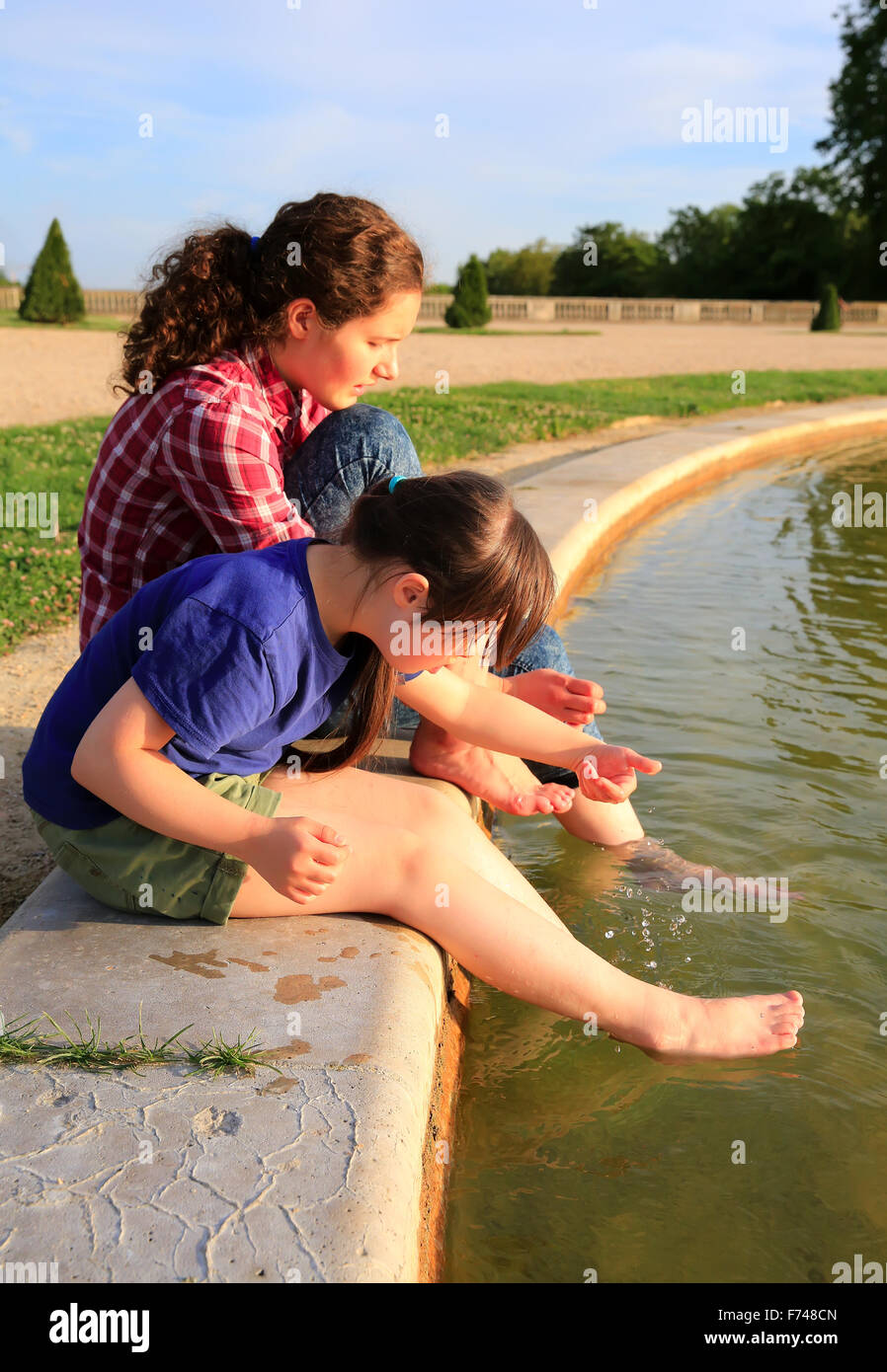 Young girls playing with the fountain Stock Photo - Alamy