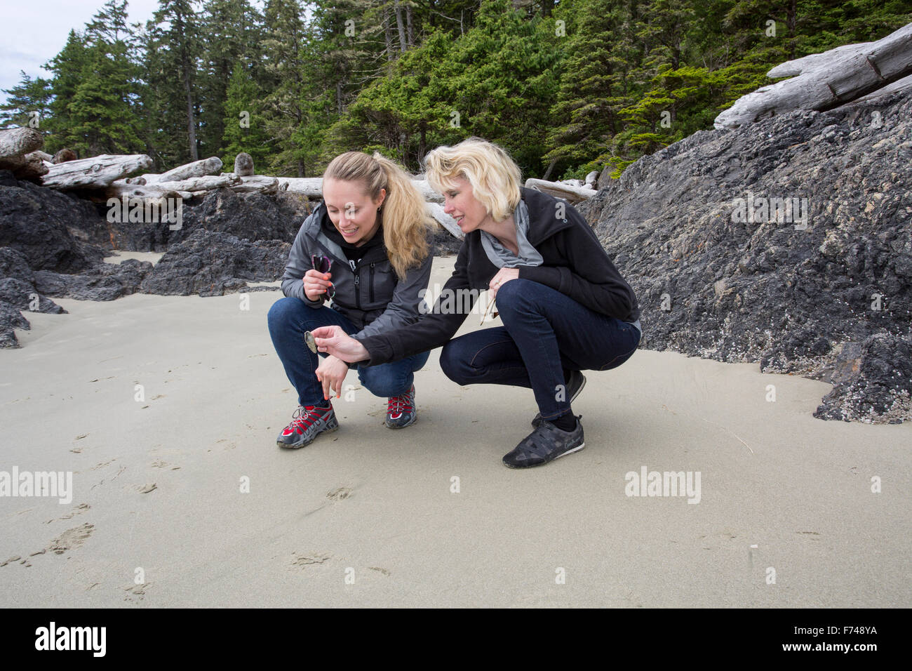 Canada, British Columbia, Vancouver Island, Pacific Ocean, Pacific Rim National Park Reserve, 2 women looking at shell Stock Photo