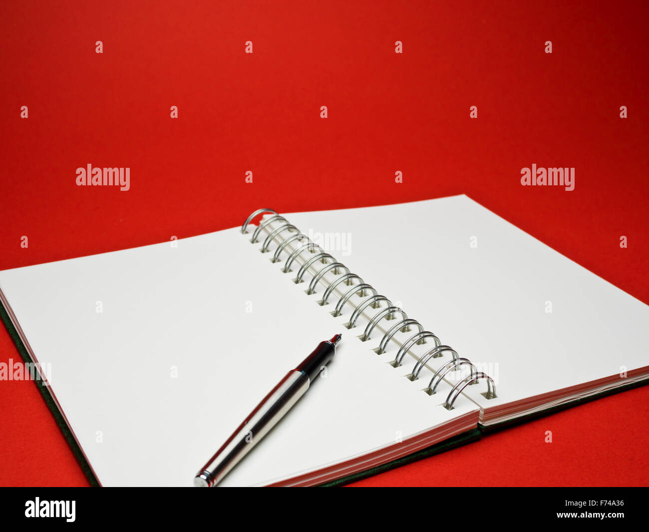 white sketchbook with silver metallic ball point pen on red background Stock Photo