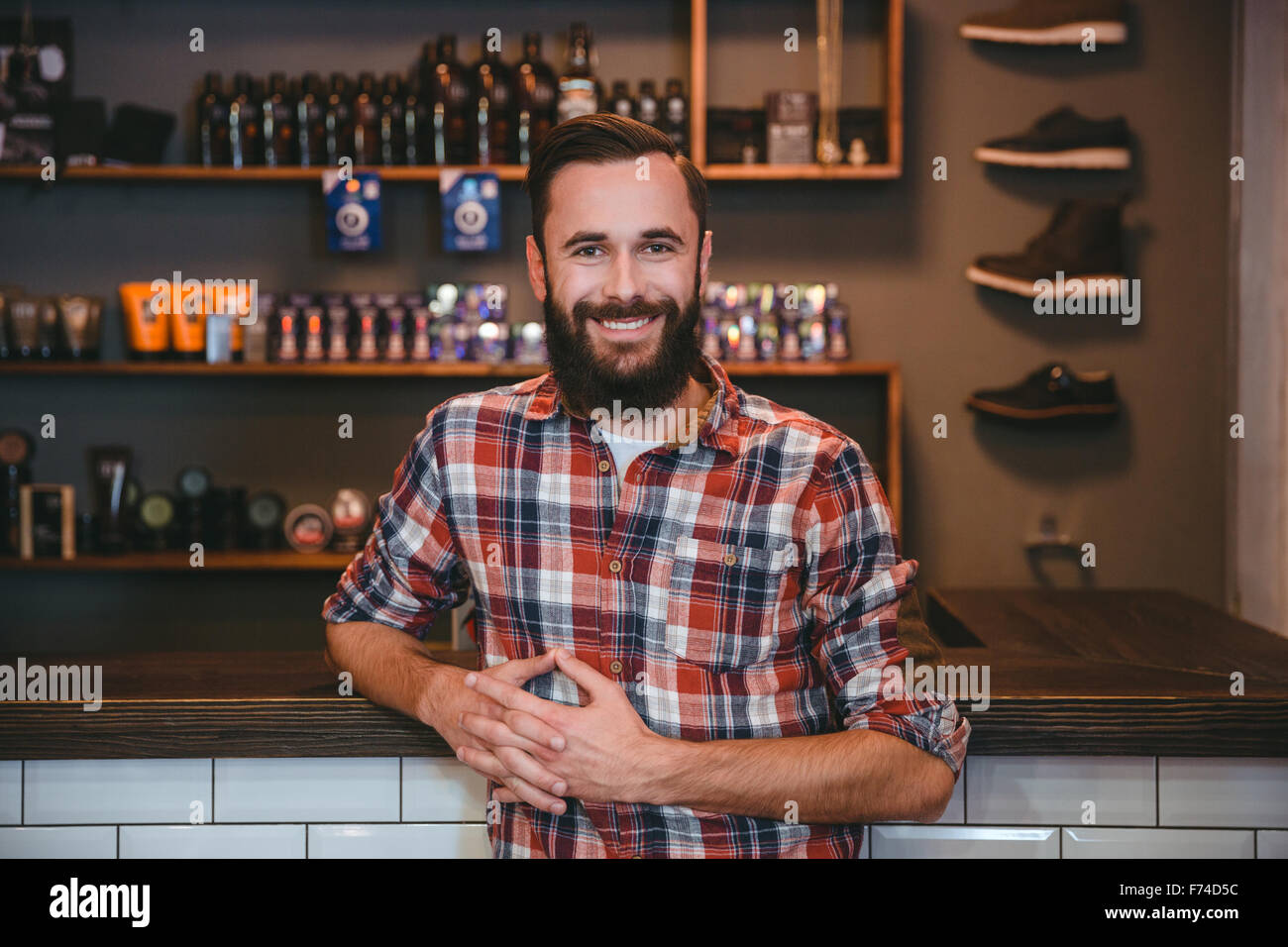 Joyful smiling content  bearded man in checkered shirt posing in barbershop Stock Photo