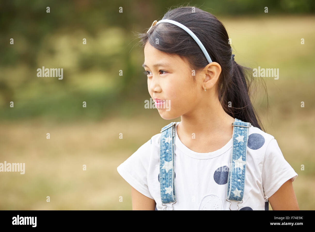 Asiatic girl with diadem and suspenders looks sceptical Stock Photo