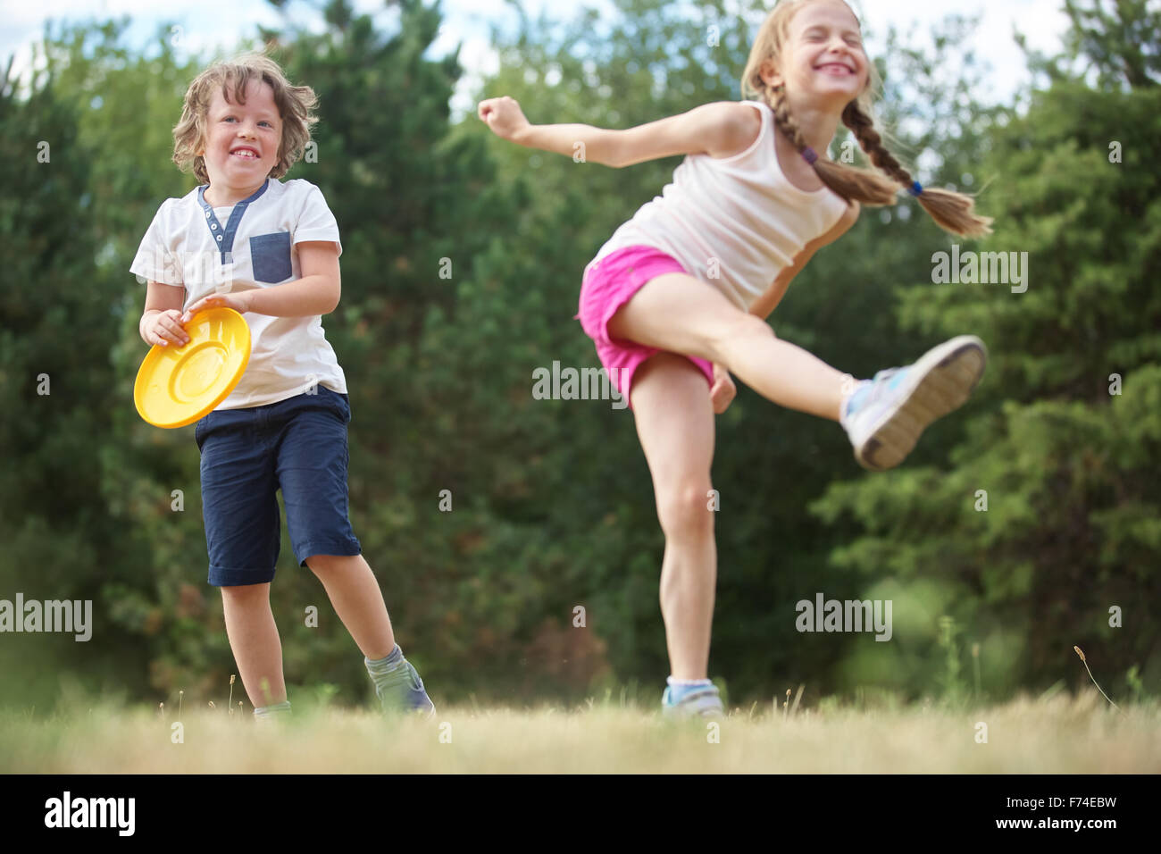 Girl and boy play happily with their frisbee and have fun Stock Photo