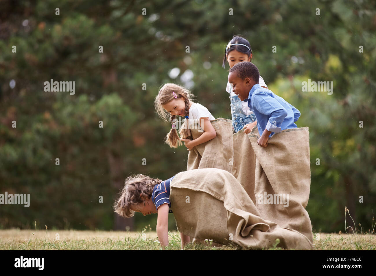 Group of interracial kids competing at sack race Stock Photo