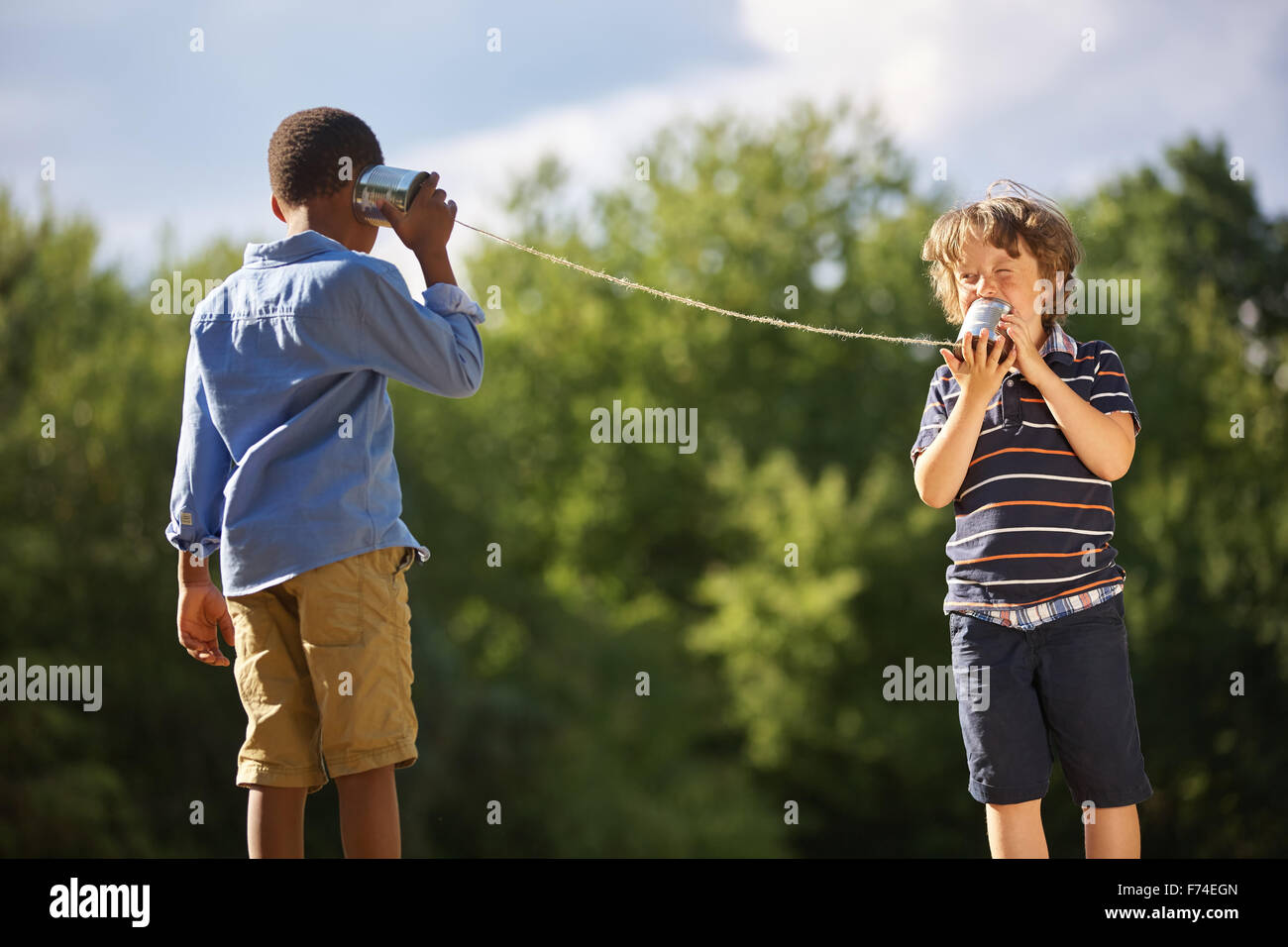 Two boys play tin can telephone in the summer Stock Photo