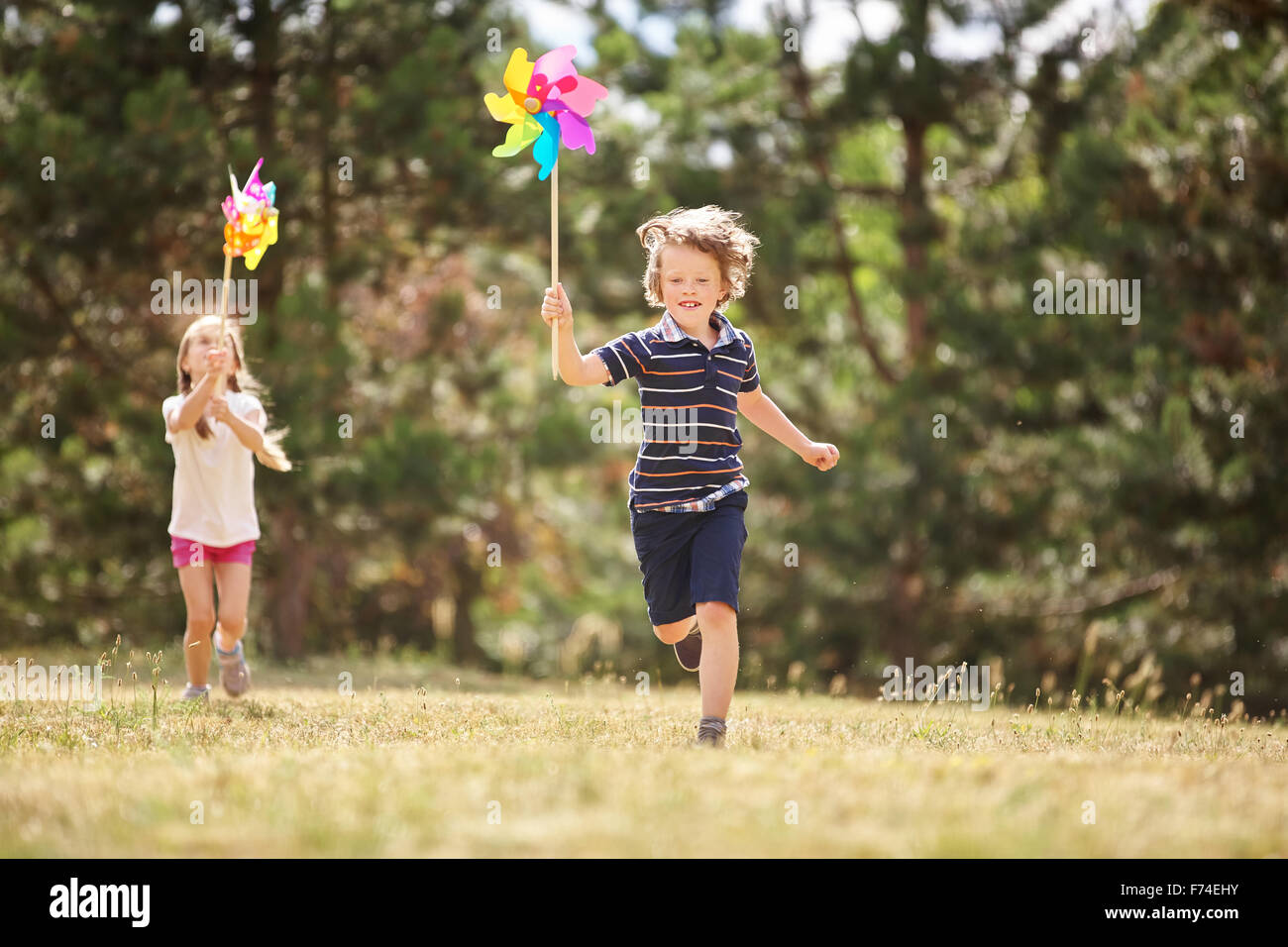 Girl and boy with pinwheels running and having fun Stock Photo - Alamy