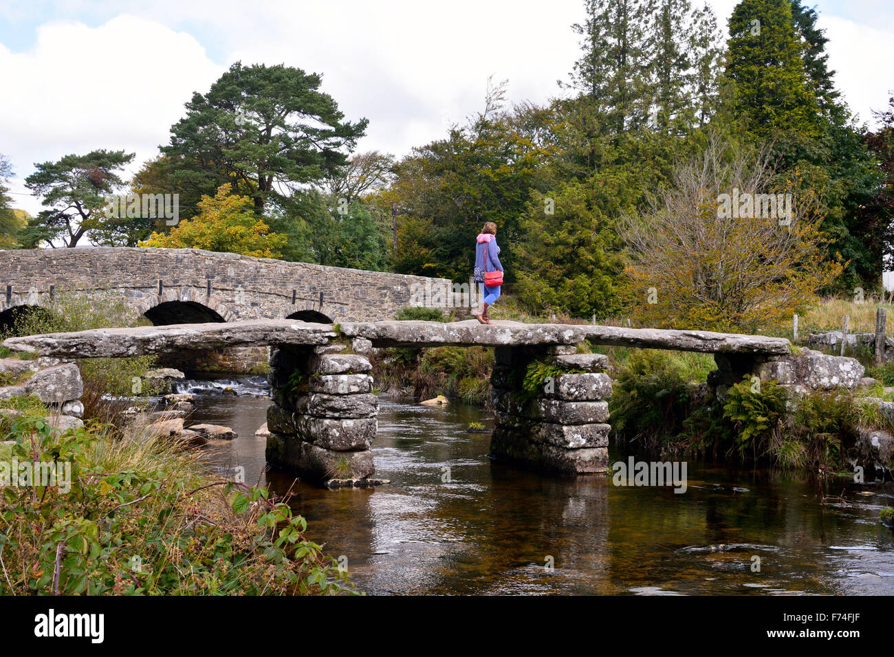 Woman crossing on the clapper bridge at Postbridge on Dartmoor, Devon ...