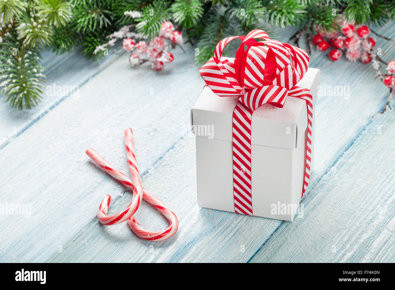 Christmas gift box, candy cane and fir tree branch on wooden table ...