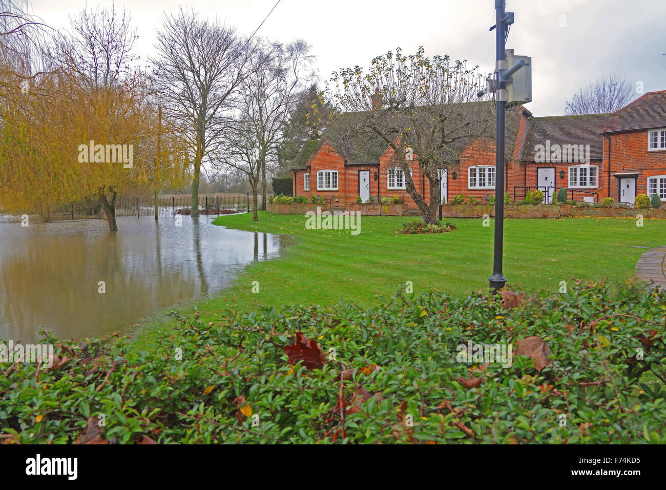Flooding along the Thames reduces a garden to a lake over the front lawn with ominous rainclouds in the background. Stock Photo