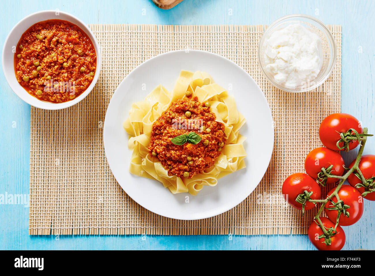Tagliatelle with Bolognese sauce on white plate and blue wooden table Stock Photo