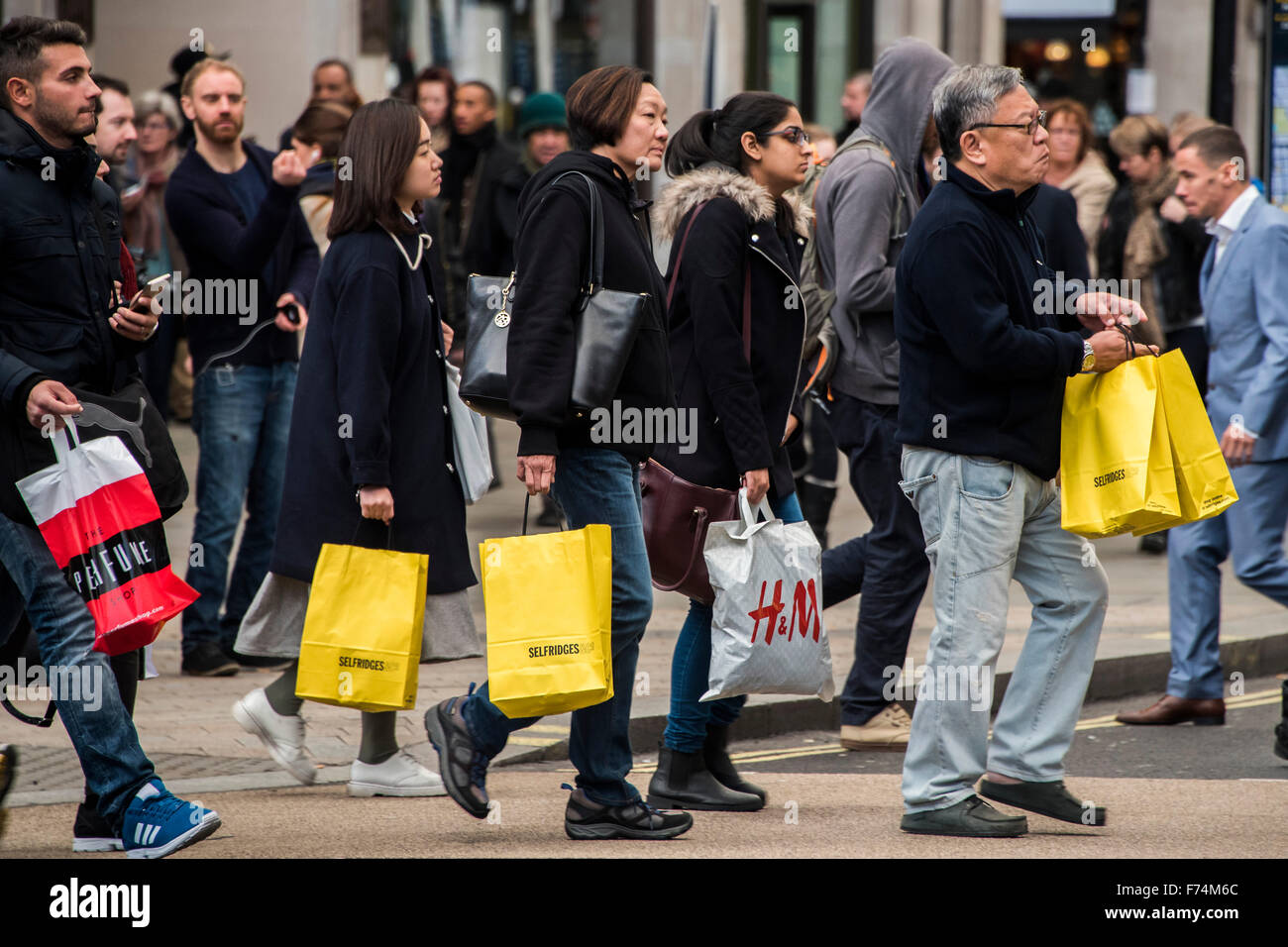 Shoppers cross Oxford Circus, some rushing and some laden with bags, as Oxford street prepares its discounted offerings for Black Friday. Stock Photo