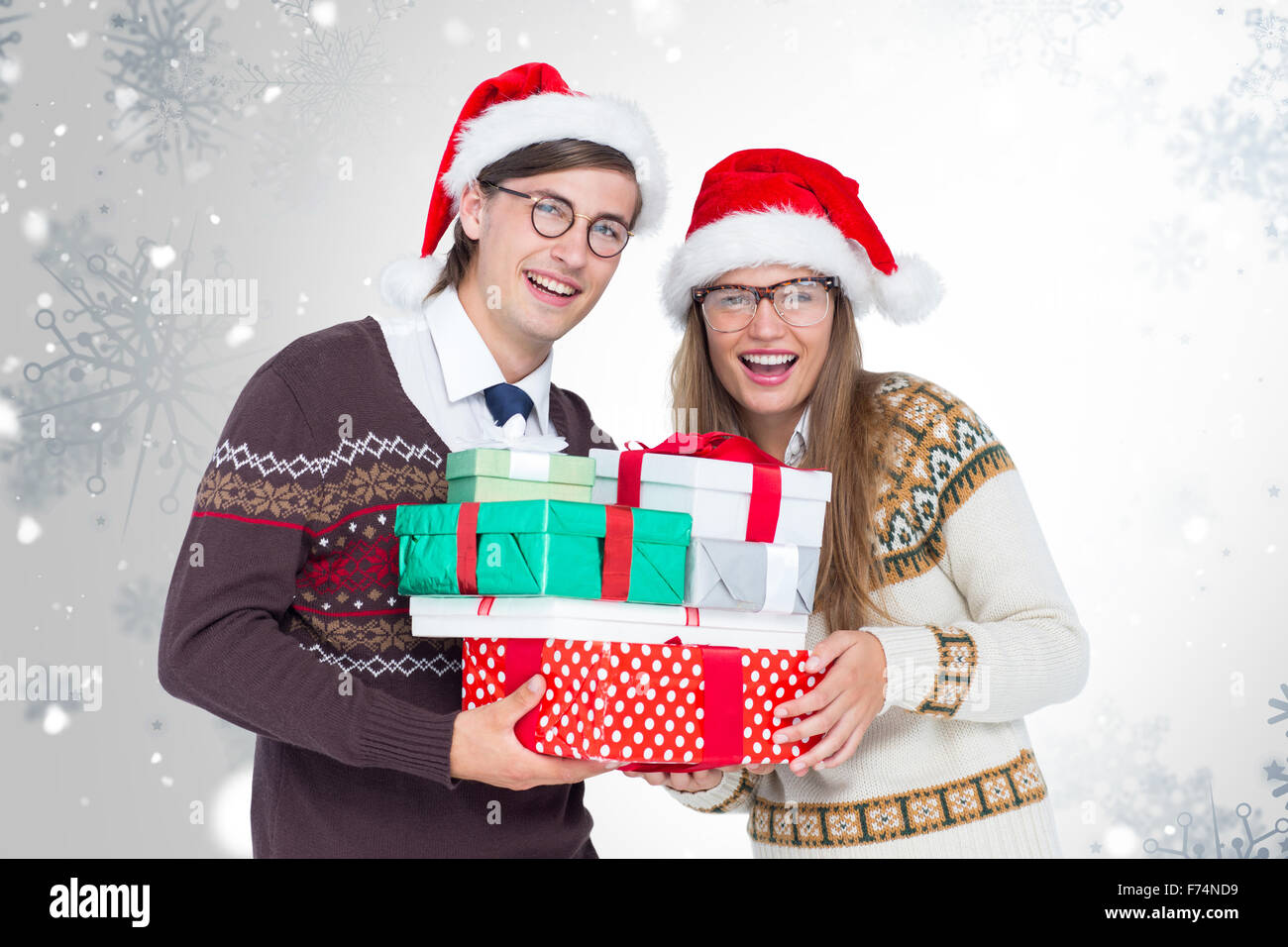 Composite image of portrait of smiling man and woman wearing santa hats and holding gifts Stock Photo