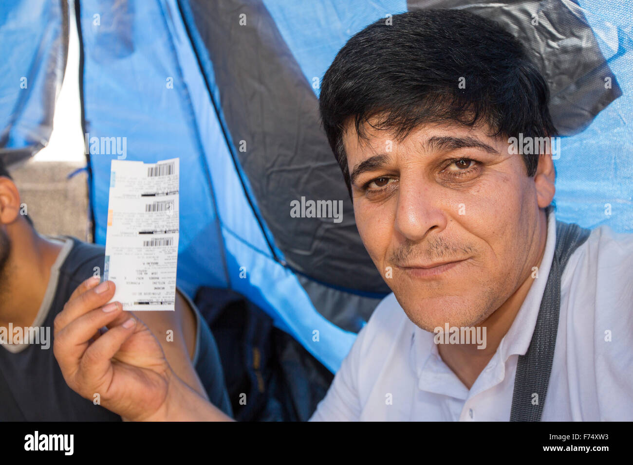 Syrian migrants fleeing the war and escaping to Europe,  who have landed on the Greek island of Lesvos on the north coast at Efthalou, here holding up ferry tickets that will allow them off the island to the Greek mainland. Up to 4,000 migrants a day are landing on the island and overwhelming the authorities. They are traficked by illegal Turkish people traffickers who charge up to $2,000 per person for a half hour ride in an overcrowded inflateable boat from the Turkish mainland to Lesvos. Stock Photo