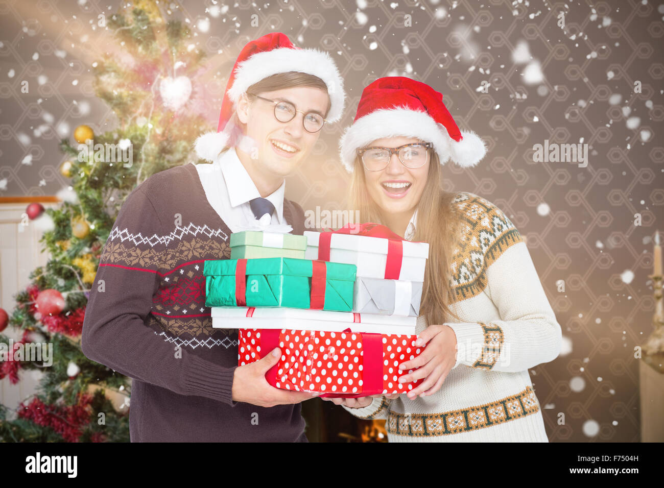 Composite image of portrait of smiling man and woman wearing santa hats and holding gifts Stock Photo