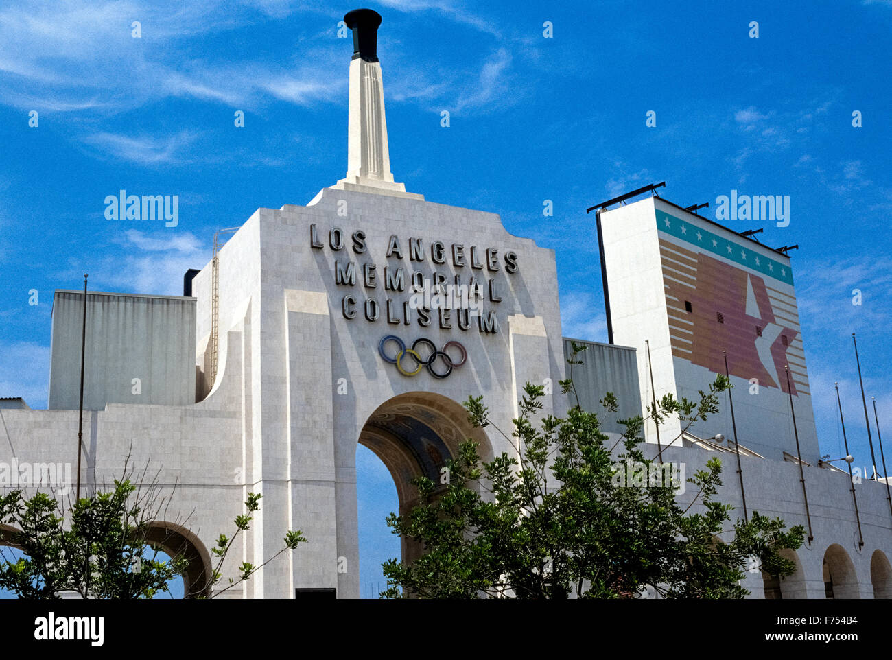 The Los Angeles Memorial Coliseum is a venerable outdoor sports stadium in Southern California, USA, that was host to the Summer Olympic Games in 1932 and 1984. Ever since opening in 1923 it has been the home stadium of the USC Trojans, the football team of the University of Southern California. The impressive main entrance into the LA Coliseum is an archway displaying the Olympic symbol of five interlinked rings and the Olympic torch that is ignited for special events. The stadium can hold more than 93,000 spectators and has been proposed to host the Summer Olympics again in 2024. Stock Photo