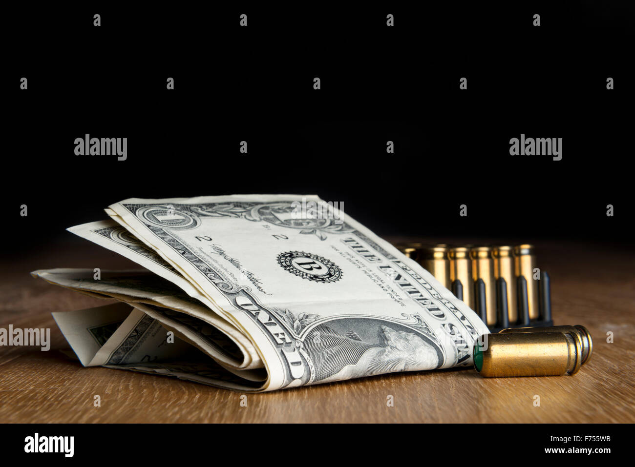 Image of dollar bills with pistols cartridges on a table Stock Photo