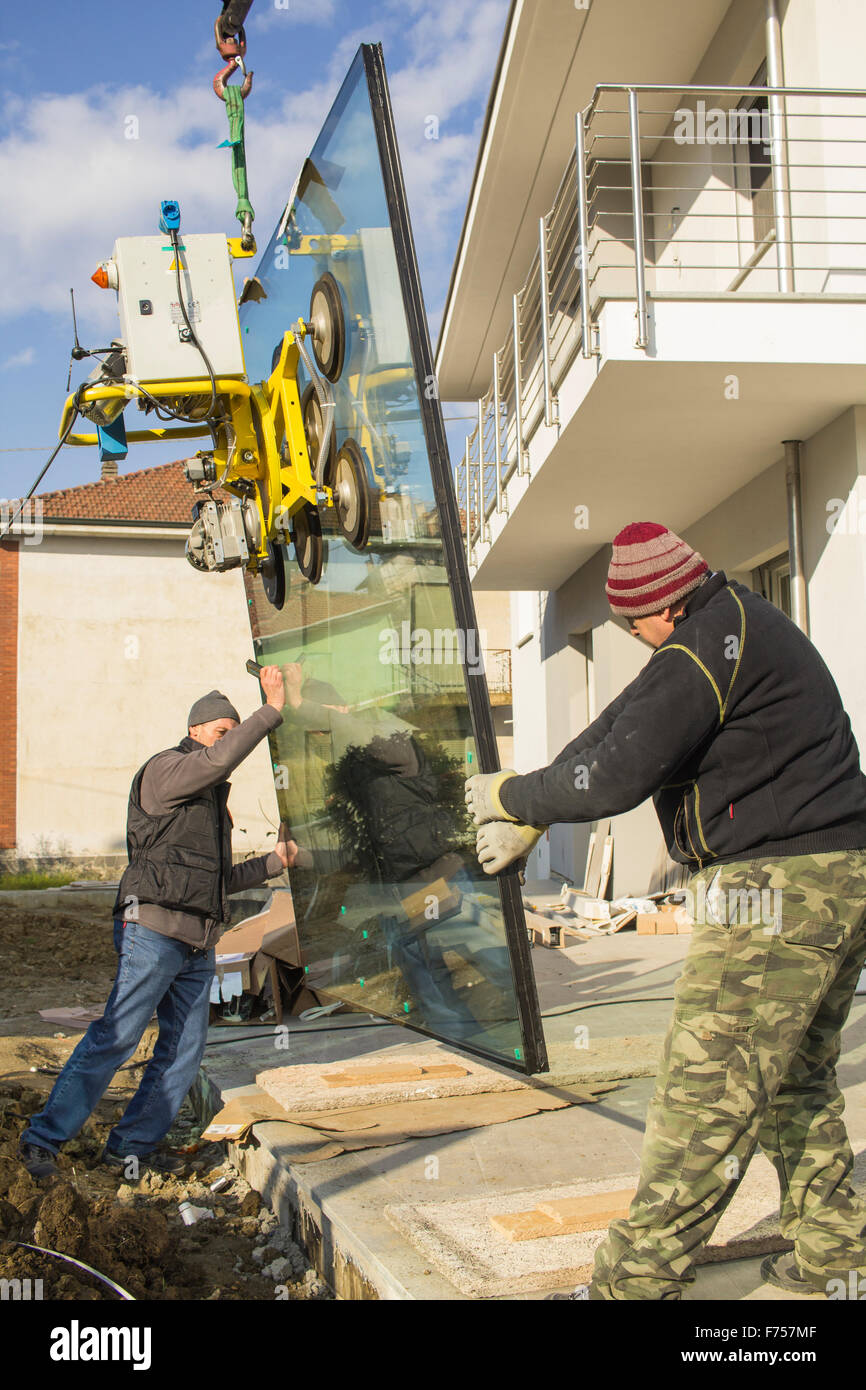 Construction workers installing new windows in a house under construction in the Northern Italy. Stock Photo