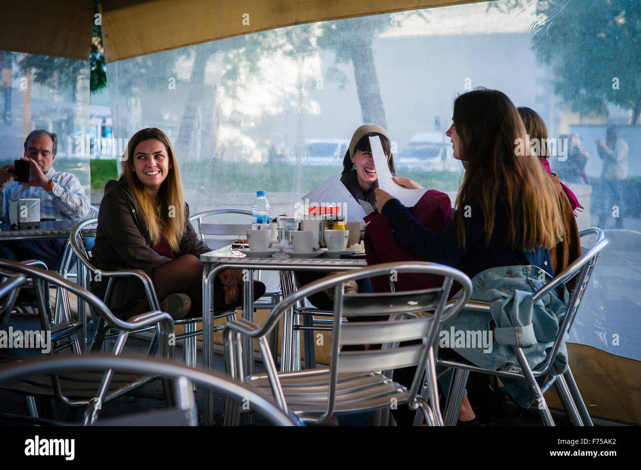 A group of students hang out in the covered area of a café on Plaça de Castella  in the El Raval district of Barcelona, Spain. Stock Photo