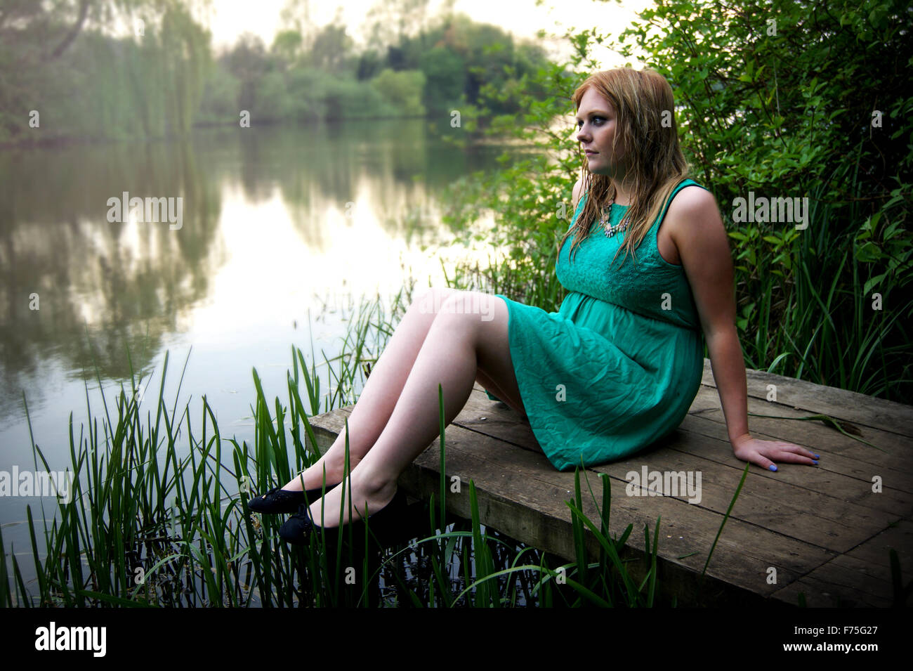 woman with wet hair sat next to lake Stock Photo