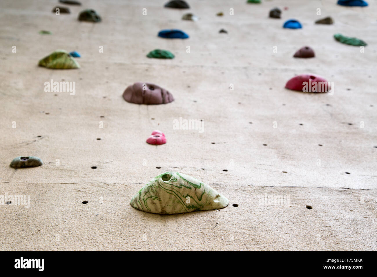 shallow depth of field looking up a climbing wall focused on the foot grip closest to the camera Stock Photo