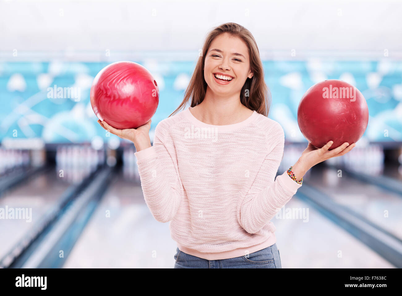 Happy girl holding two bowling balls in bowling club Stock Photo