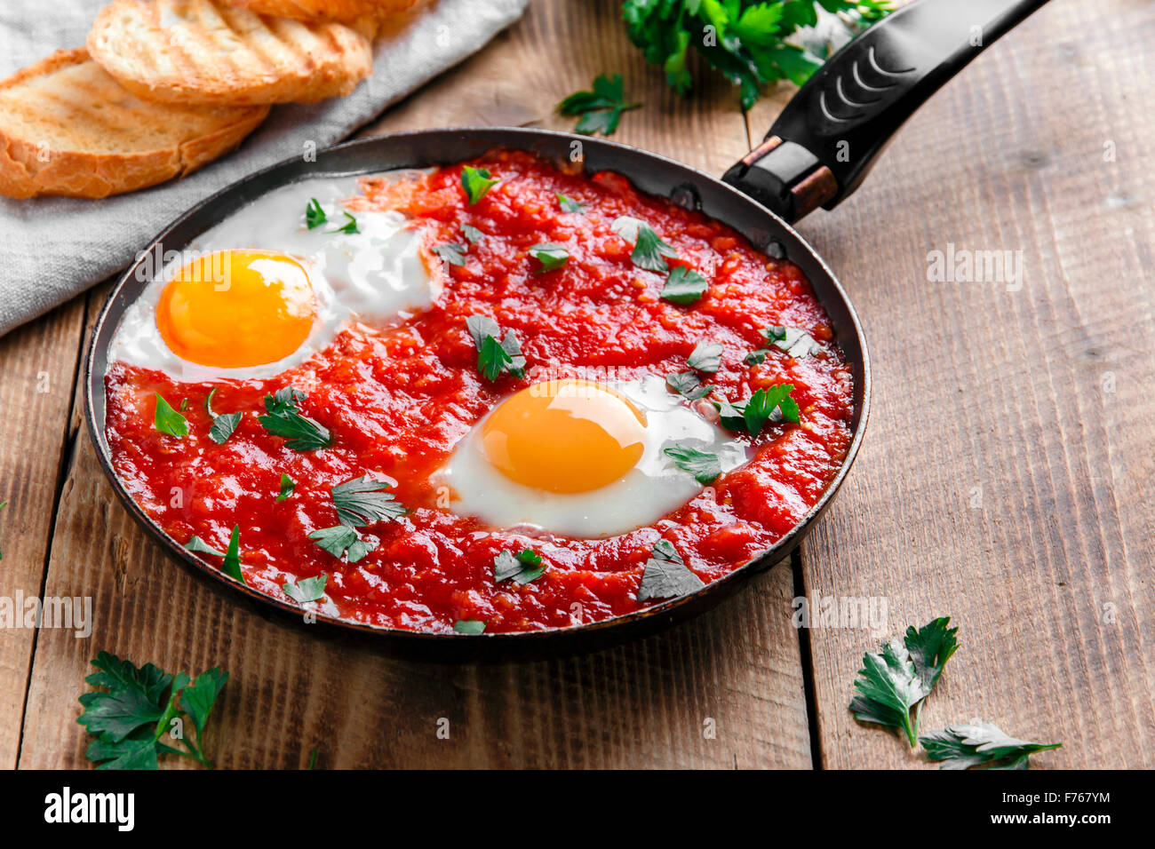 fried eggs in tomato sauce in the pan Stock Photo