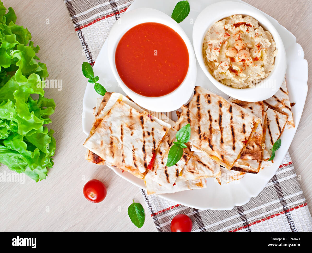 Mexican Quesadilla sliced with vegetables and sauces on the table. Top view. Stock Photo
