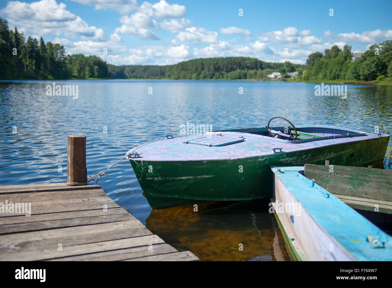 Old motor boat tied to a wooden pier on the lake Stock Photo - Alamy