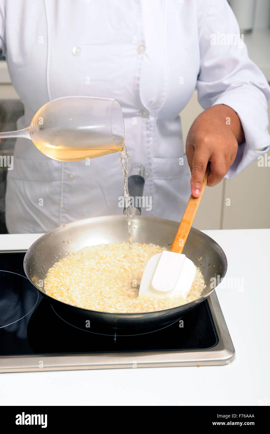 Chef cooking risotto pouring white wine into the pan Stock Photo Alamy