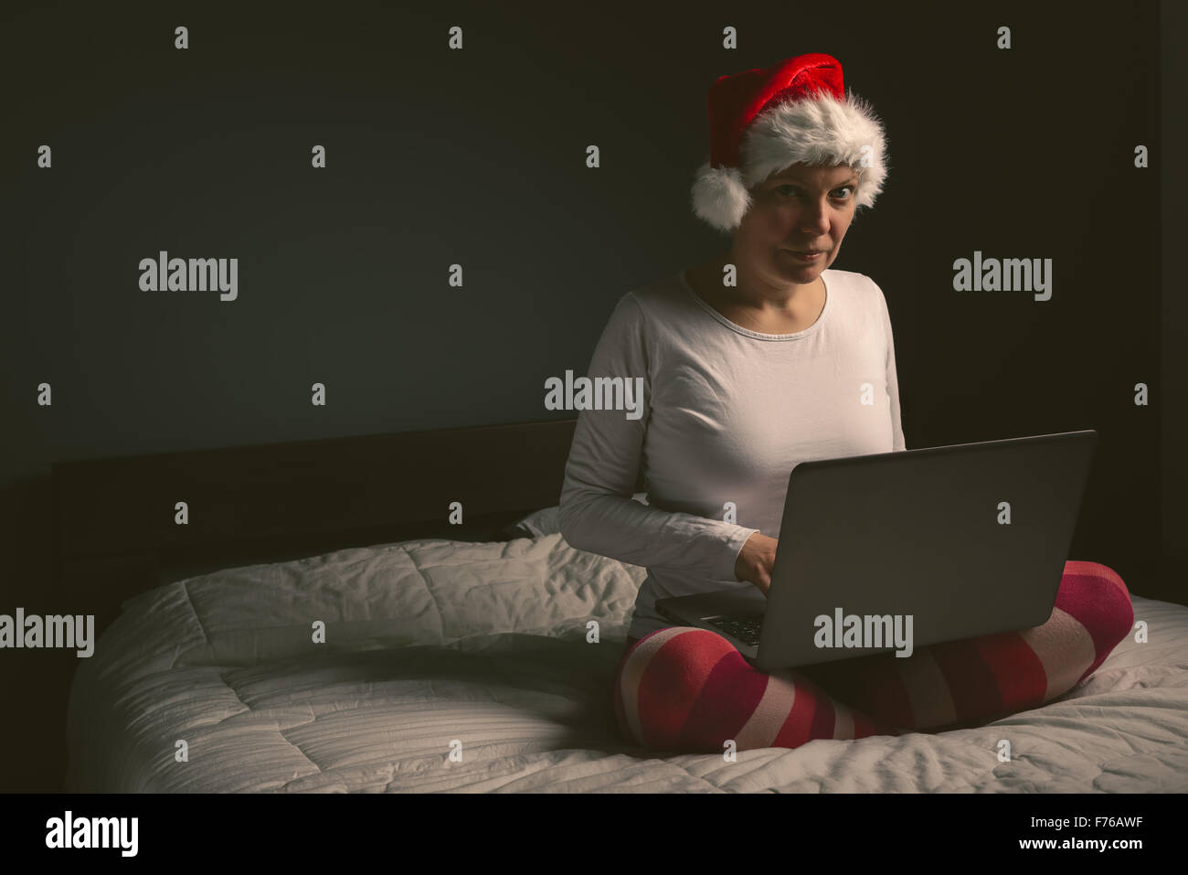 Lonely woman browsing internet on Christmas eve, adult female using laptop computer to access social network sites, retro toned Stock Photo
