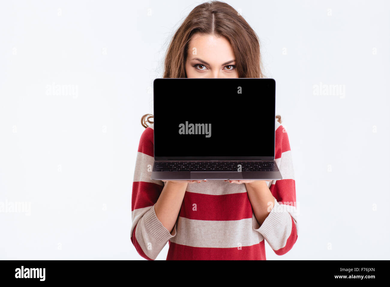 Portrait of a young woman covering face with blank laptop computer ...