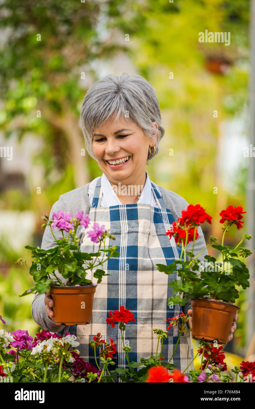 Mature woman in a greenhouse holding flowers Stock Photo - Alamy