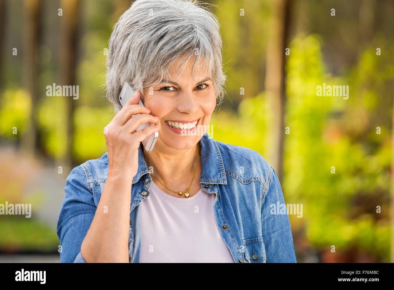 Beautiful mature woman gardening and talking at phone Stock Photo