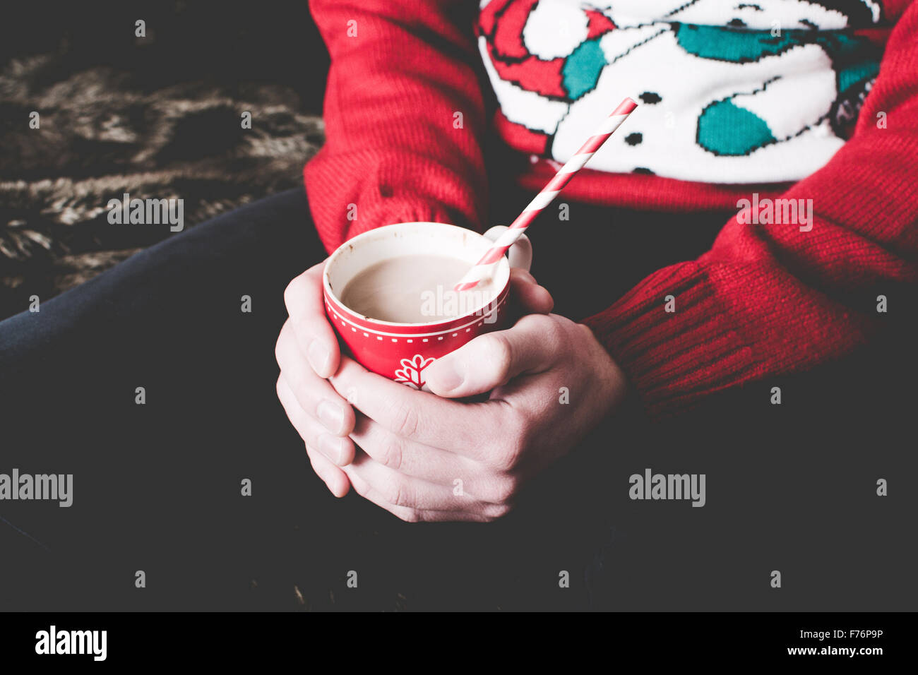 Man wearing a Christmas jumper and holding a hot chocolate Stock Photo
