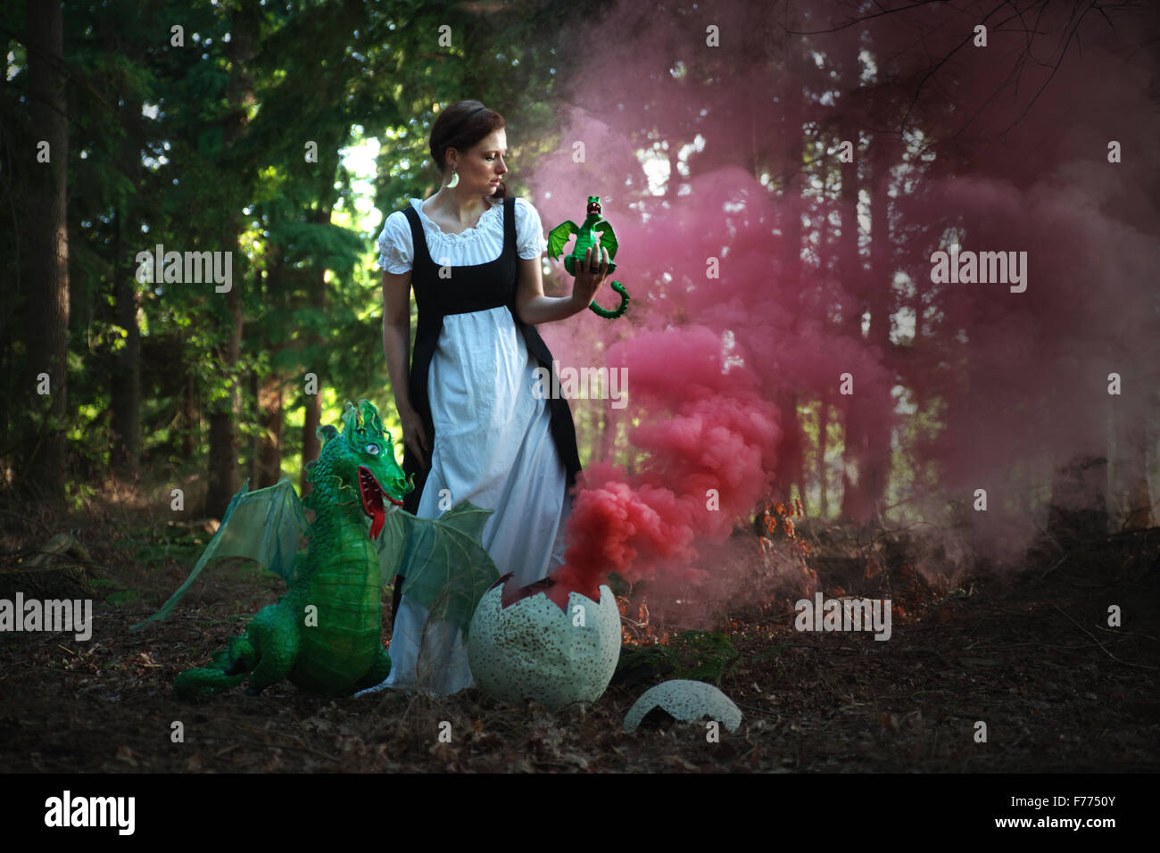 Woman with dragon baby, dragon beside red smoke coming out of the egg, fantasy Stock Photo