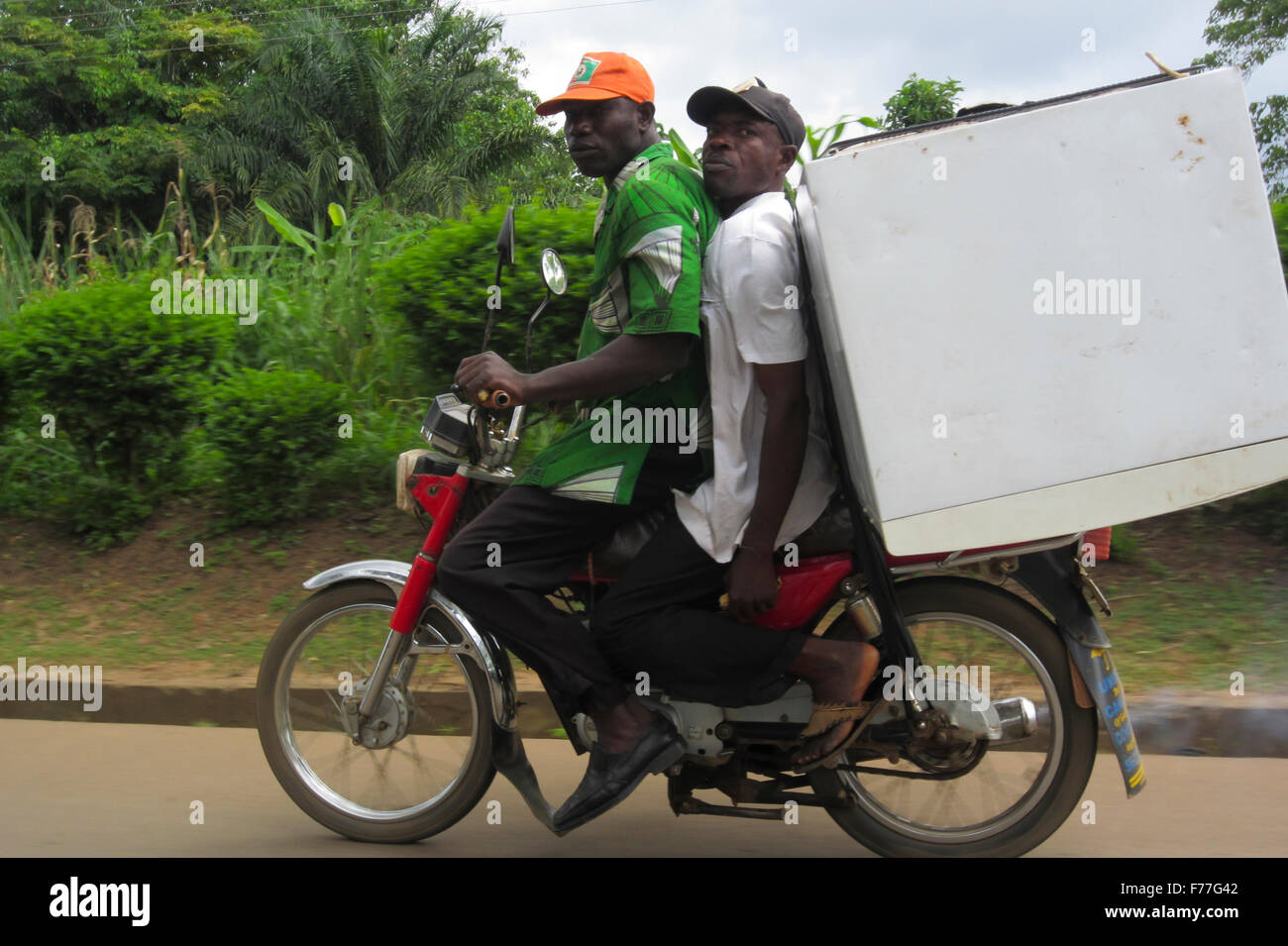 Two friends riding a motorbike, transporting a fridge in Nigeria Stock  Photo - Alamy