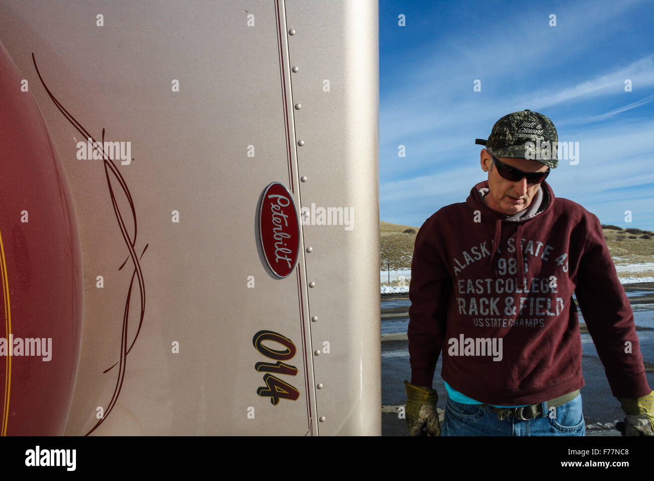 British truck driver in Wyoming, USA beside the upturned hood of his Peterbilt 379 American truck Stock Photo