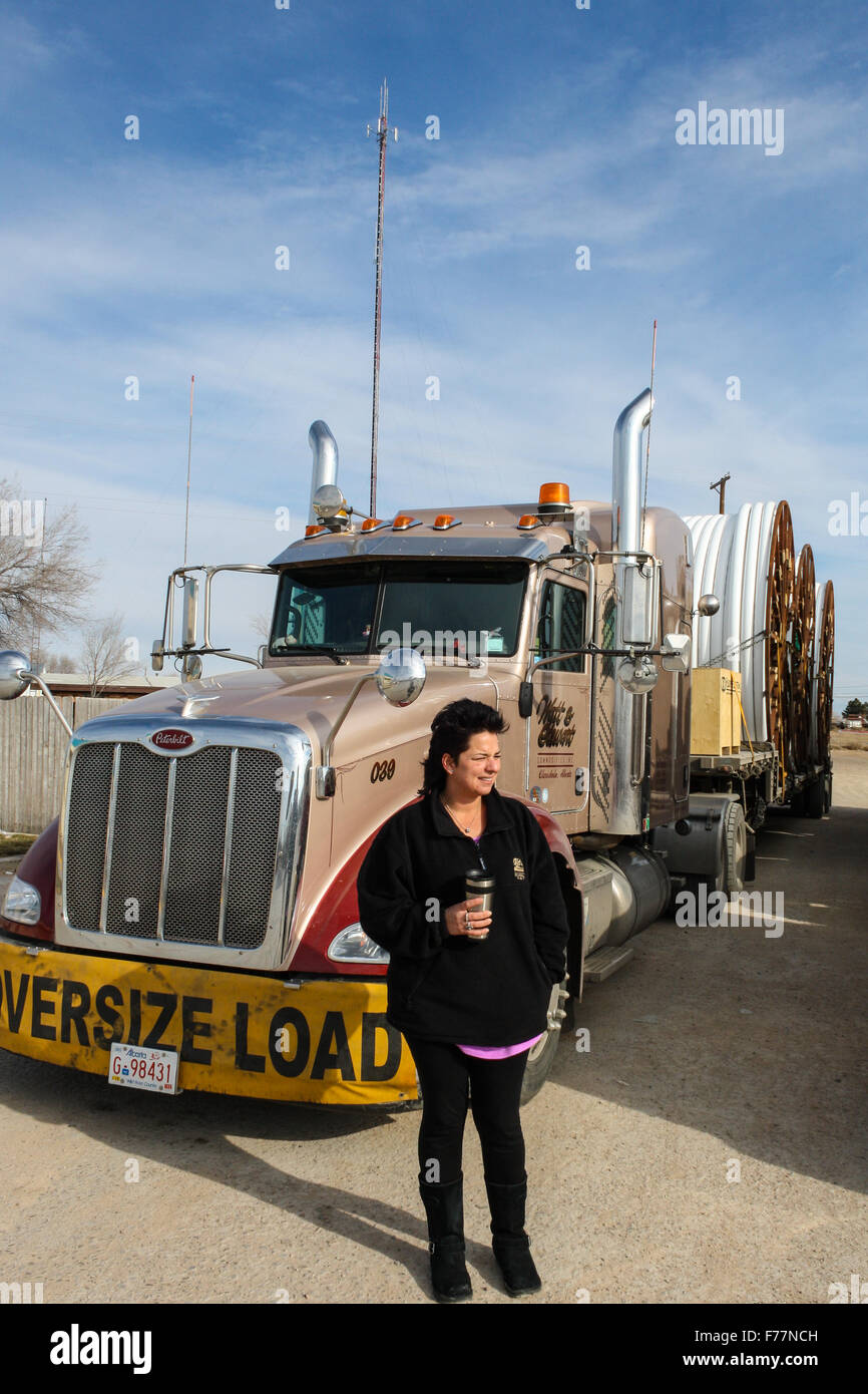 Female, Dutch truck driver poses beside her 'Watt and Stewart' Canadian company Peterbilt trucks