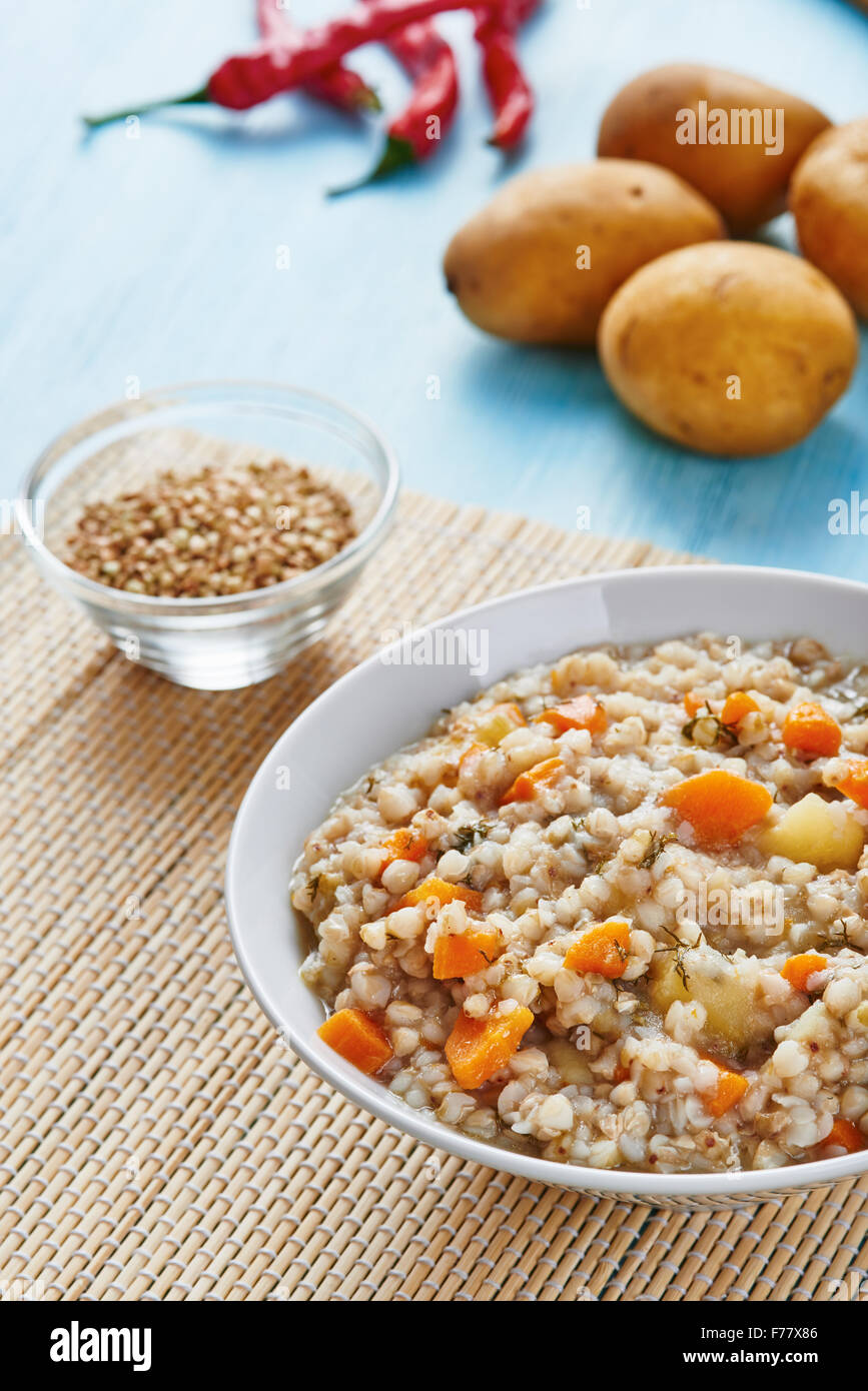Buckwheat soup in white bowl on wooden blue table - gluten free food Stock Photo