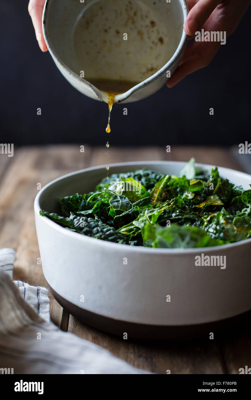 Pouring salad dressing over kale Stock Photo