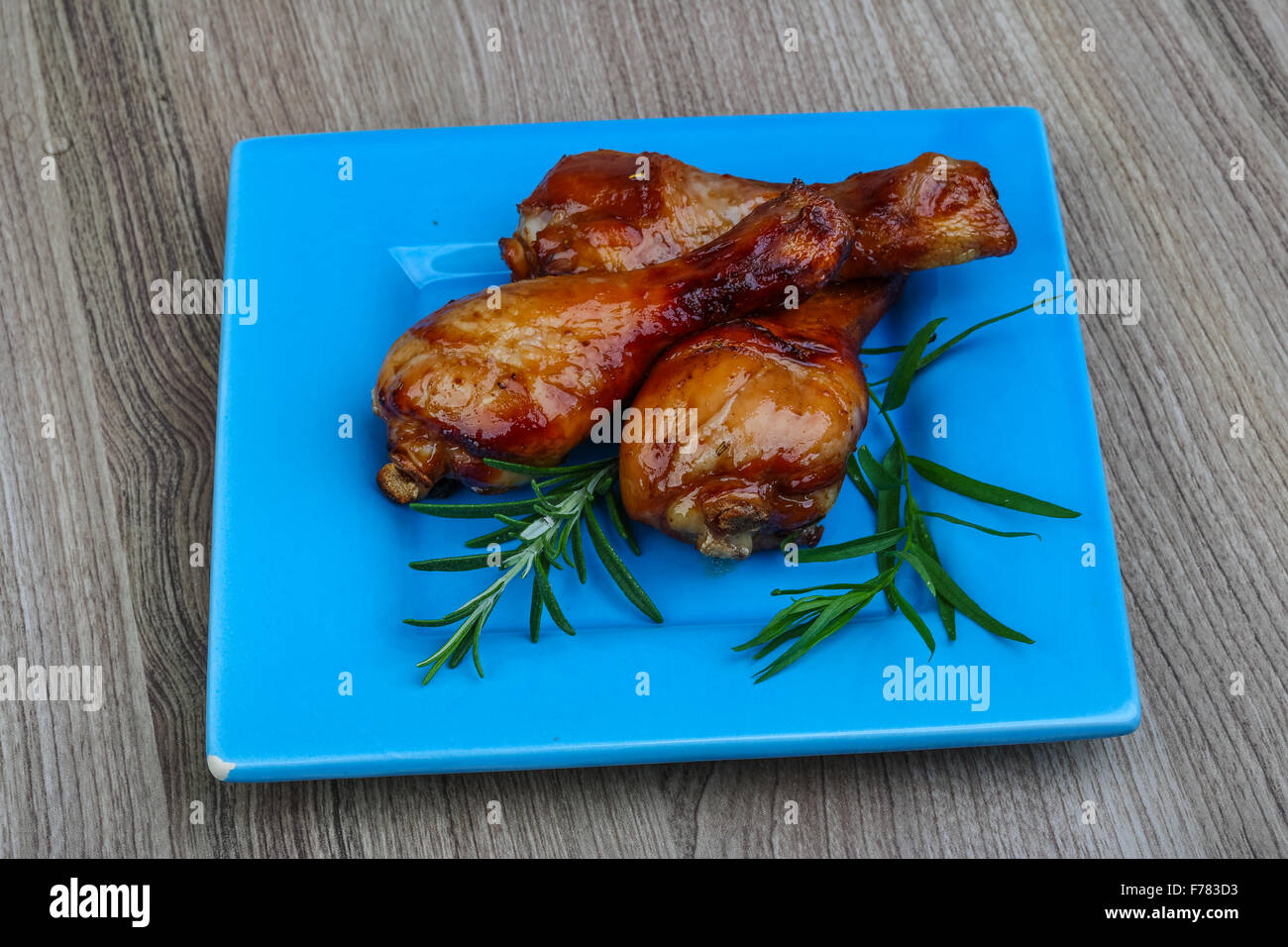 Roasted chicken legs with rosemary on the wood background Stock Photo