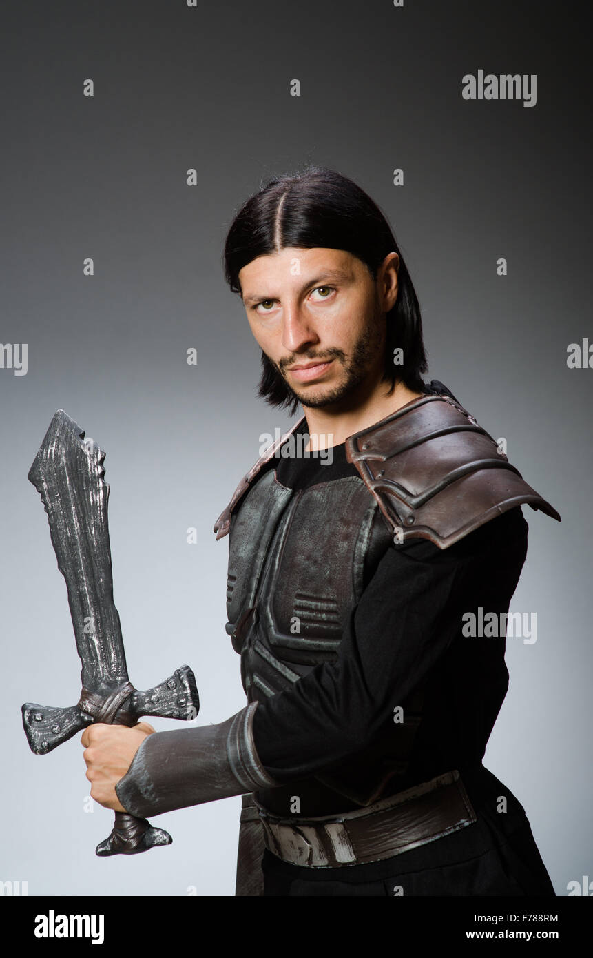 Angry knight with sword against dark background Stock Photo - Alamy